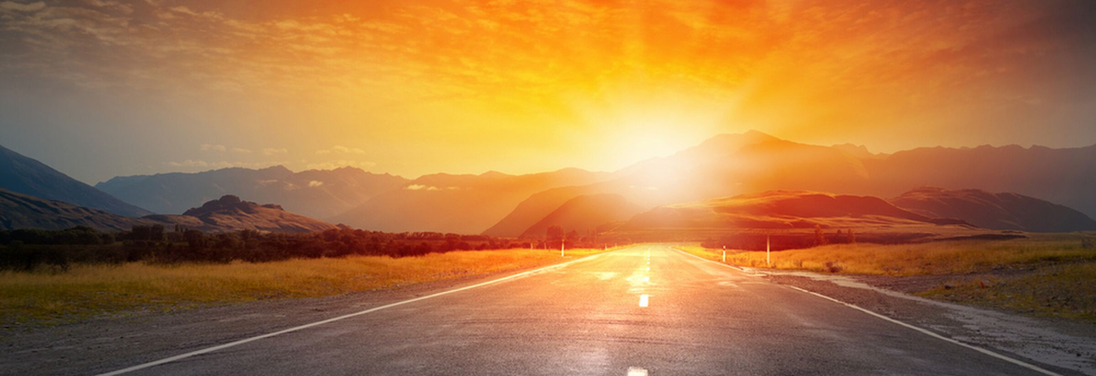 Long open road with Mountains and Sunset in the background